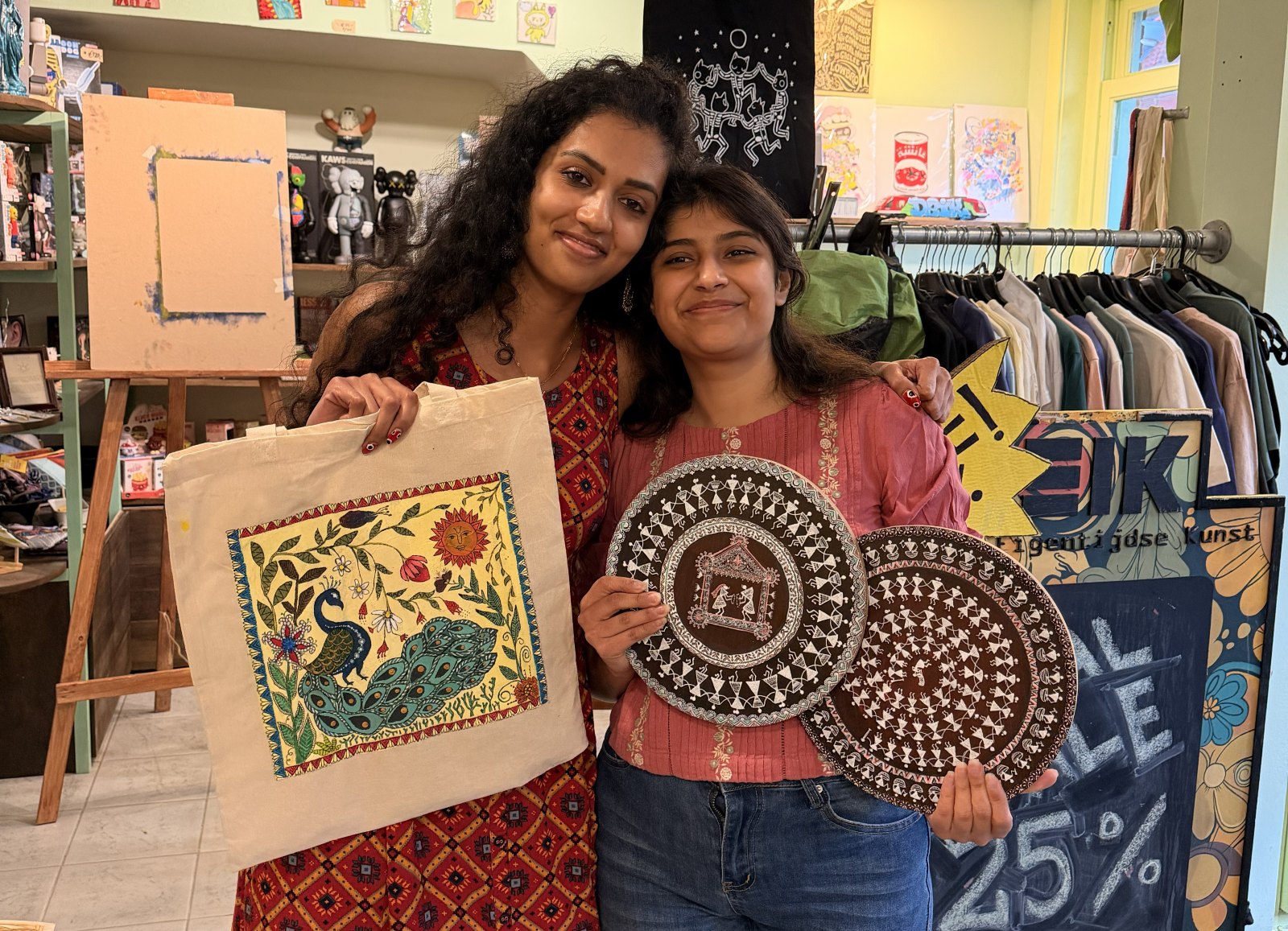 Sukanya and Pallavi holding their finished Madhubani tote bag and Warli plates in the studio