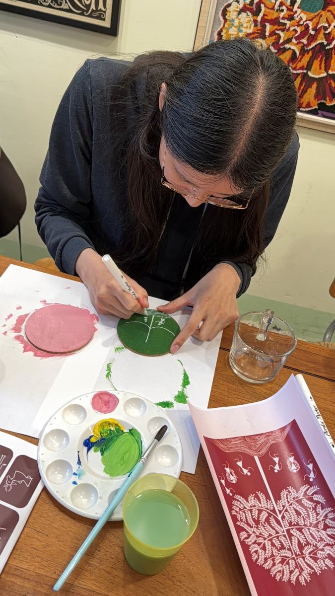 Painting a Warli motif onto a coaster
